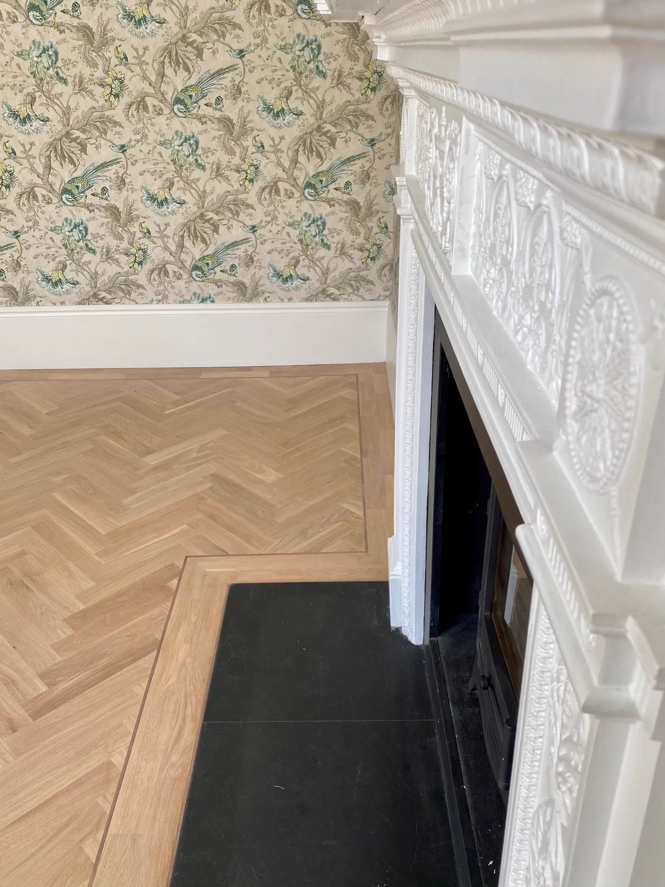 Herringbone parquet with border detail beside a period fireplace